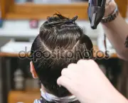 Hairstylist drying hair of male client using hairdryer and comb